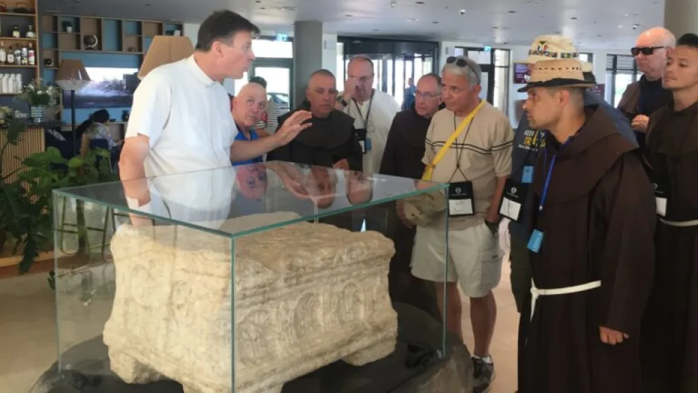 The Rev. Eamon Kelly in the lobby of the Magdala Hotel, speaking to a group of pilgrims by the Magdala Stone. Photo by Diana Bletter