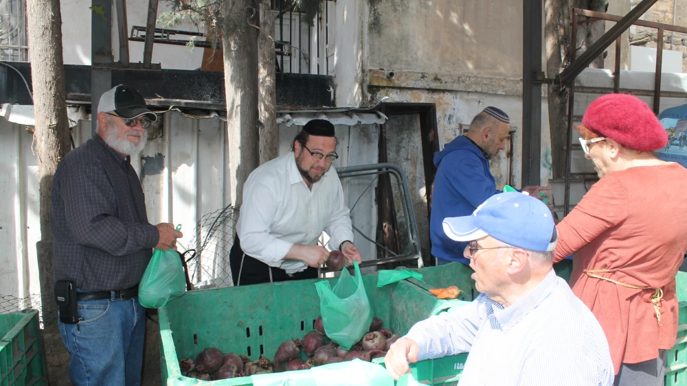 Rabbi Chaim Goldsmith (center), who moved to Jerusalem 22 years ago from Manhattan, helps to pack food. Credit: Courtesy.