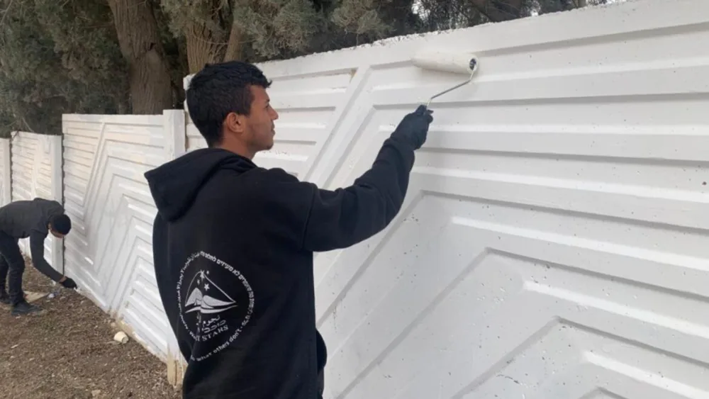 Bedouin men painting over graffiti at a Jewish cemetery in Moshav Nevatim. Photo courtesy of Desert Stars.