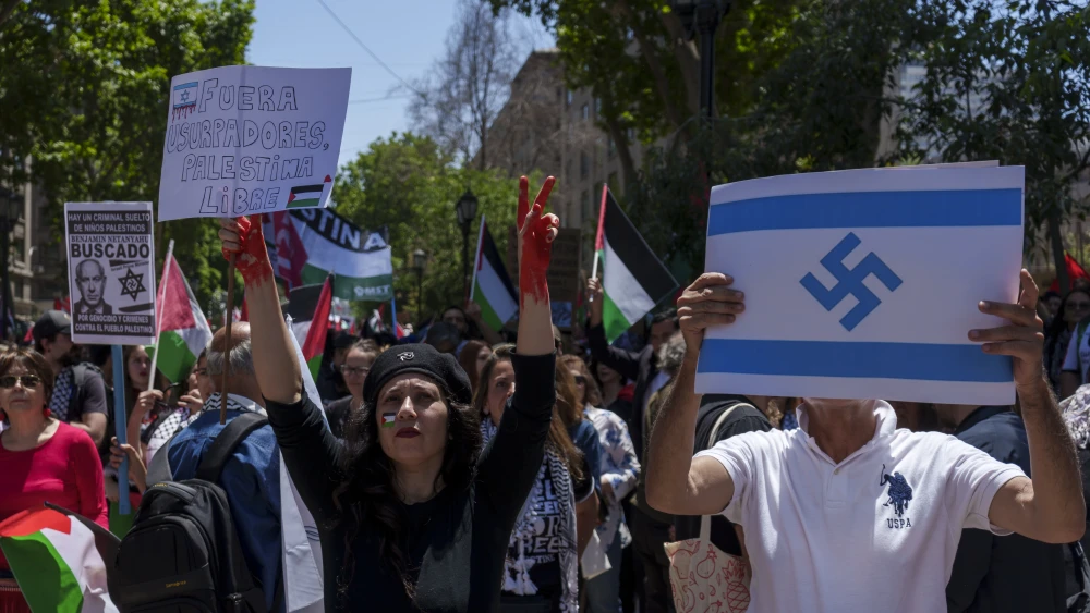 SANTIAGO, CHILE - NOVEMBER 04: A woman holds a sign that says Usurpers out, free Palestine next to a man holding an Israeli flag with the Nazi symbol during the march called by pro-Palestine organizations in Santiago on November 4, 2023 in Santiago, Chile. Entering the third week of the conflict, the Israeli army has expanded its military assault. The Gaza Strip is under heavy bombing from Israel in response to the large-scale attack carried out on October 7 by Hamas in Israel. The international community is stepping up pressure for a humanitarian truce. (Photo by Sebastián Vivallo Oñate/Agencia Makro/Getty Images)