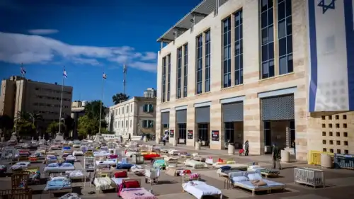 People walk between hundreds of beds, each symbolizing a captive held by Hamas in the Gaza Strip, outside Jerusalem City Hall, Oct. 30, 2023. Photo by Yonatan Sindel/Flash90.