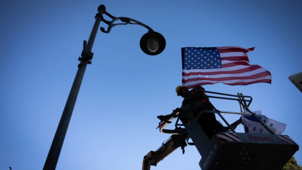 A Jerusalem Municipality worker hangs American flags in Jerusalem on July 10, 2022, in preparation for the upcoming visit of U.S. President Joe Biden. Photo by Yonatan Sindel/Flash90.