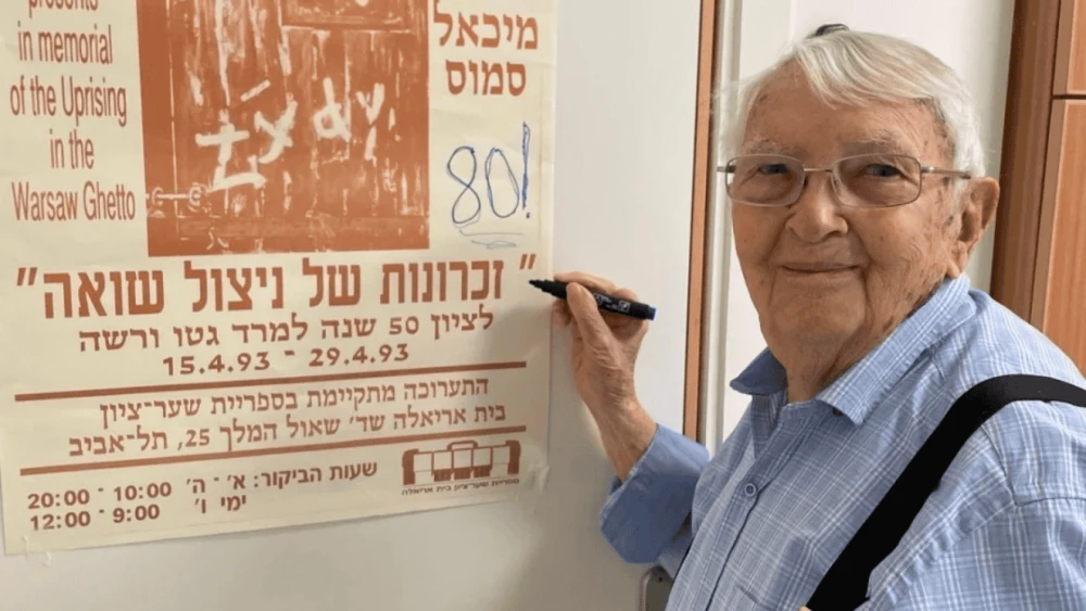 Michael Smuss points to a poster commemorating the 50th anniversary of the Warsaw Ghetto Uprising in 1993. Credit: Courtesy.