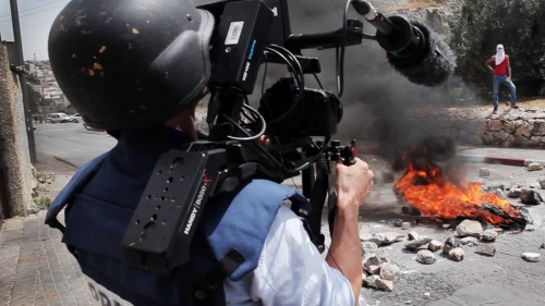 A photojounalist records a video of Palestinian rioters. Photo: Ruben Salvadori / Flash 90