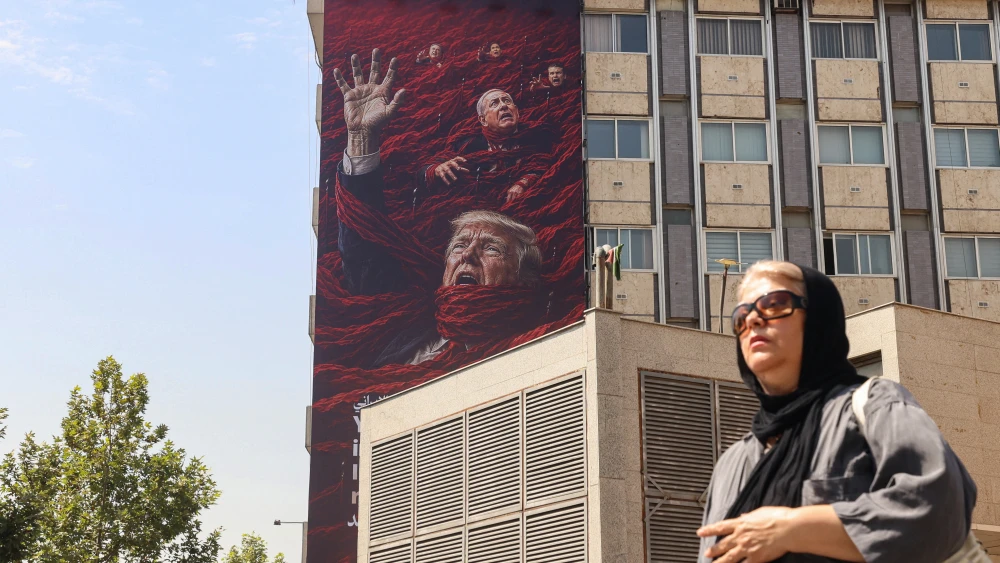 An Iranian woman walks past a propaganda billboard featuring U.S. President Donald Trump and Israeli Prime Minister Benjamin Netanyahu in Tehran, July 19, 2026. Photo by Atta Kenare/AFP via Getty Images.