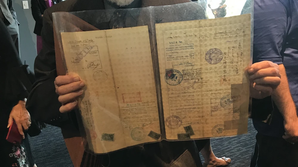 Nathan Lewin, 85, holding the original transit visas issued to him and his parents by Chiune Sugihara. Credit: Shiryn Ghermezian.