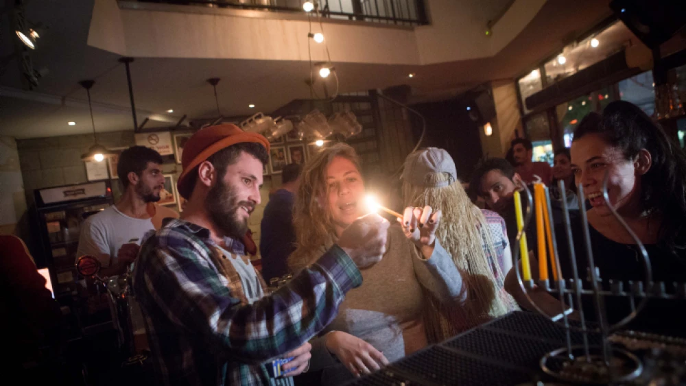 Young Israelis light candles for the Jewish holiday of Hanukkah at a bar in Tel Aviv on Dec. 8, 2015. Photo by Miriam Alster/Flash90.