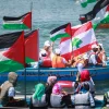 Palestinians hold flags as they ride a boat during a rally marking the fifth anniversary of the "Mavi Marmara" flotilla at the seaport of Gaza City on May 31, 2015. Credit: Aaed Tayeh/Flash90.