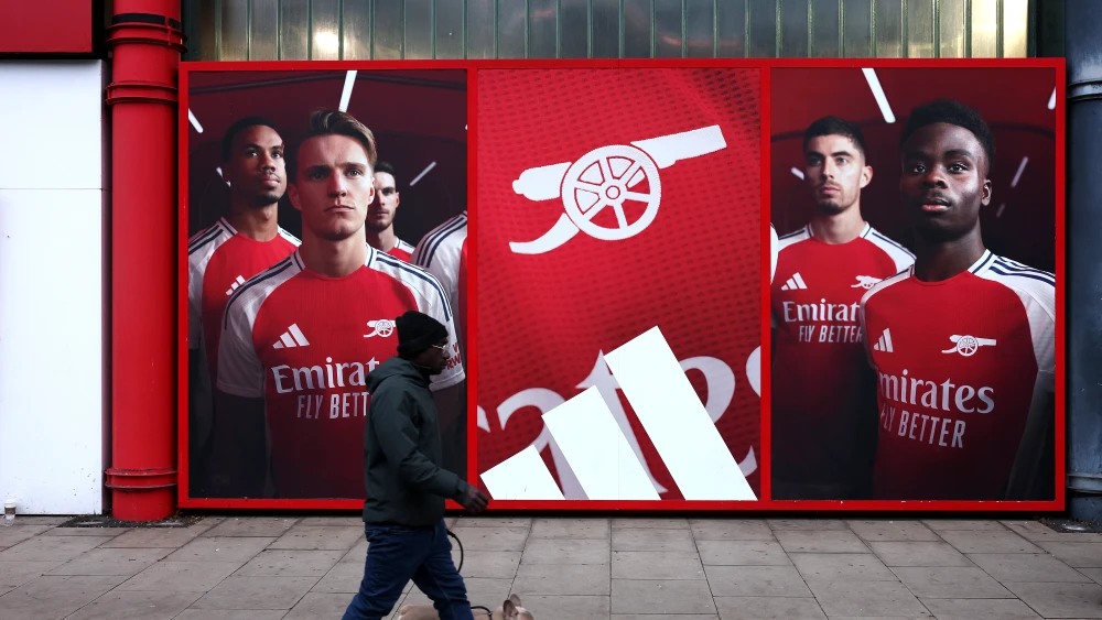 A man walks his dog outside the stadium in front of an Adidas advert ou Emirates Stadiumfeaturing Martin Odegaard and Bukayo Saka prior to the Premier League match between Arsenal FC and Aston Villa FC at Emirates Stadium on Jan. 18, 2025 in London, England. Photo by Alex Pantling/Getty Images.