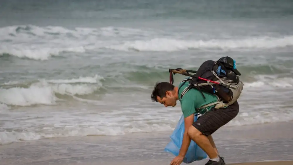 Israeli blogger Gil Drori pick up plastic bags at Beit Yanai Beach, north of Netanya, as part of his effort to raise awareness of the harmful effects of disposable plastic, Nov. 23, 2018. Photo by Meir Vaknin/Flash90.