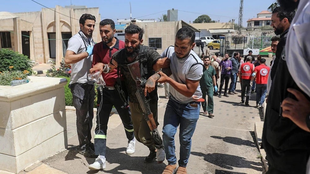 A Bedouin tribal gunman is helped to a hospital in Izra, in Syria's southern Daraa Province, after being wounded in combat against Druze fighters in nearby Sweida on July 19, 2025. Photo by Abdulaziz Ketaz/AFP via Getty Images.