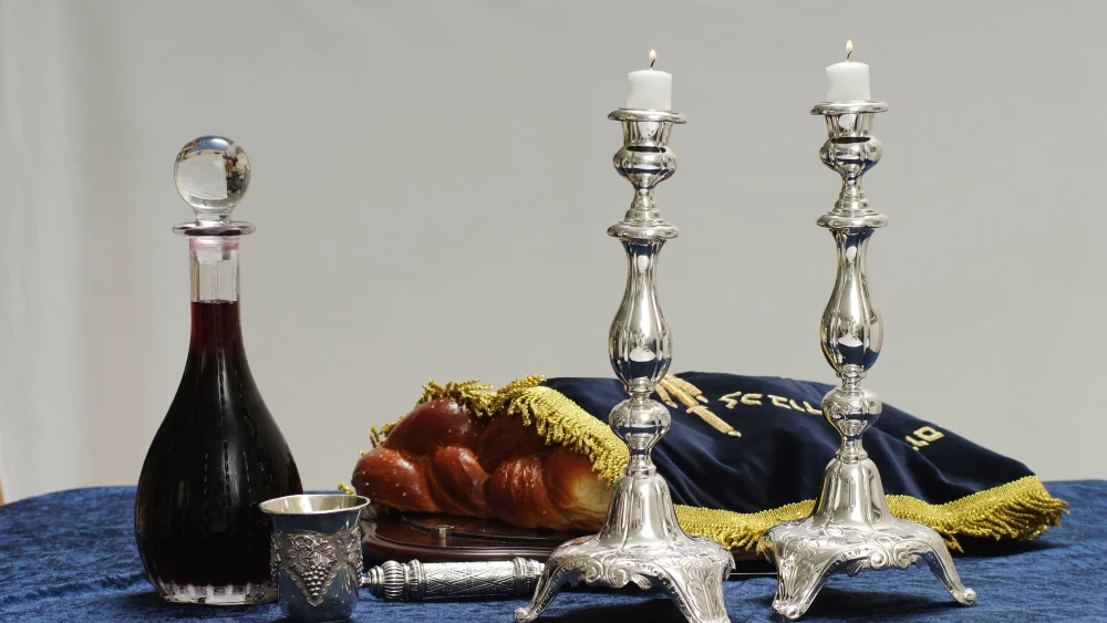 Illustration of a Shabbat table with the customary wine, challah and candles, which will all be blessed before the meal (photo was not taken on Shabbat). Photo by Mendy Hechtman/Flash90.