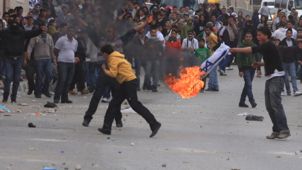Palestinians burn an Israeli flag during a “Day of Rage” riot at Qalandiya checkpoint near Ramallah in the West Bank, March 16, 2010. Photo by Issam Rimawi/Flash90.