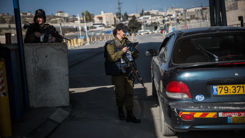 An Israeli soldier from the Erez Battalion checks IDs and Palestinian vehicles at the checkpoint to the Shuafat Refugee Camp in eastern Jerusalem on Dec. 22, 2015. Photo: Hadas Parush/Flash90.