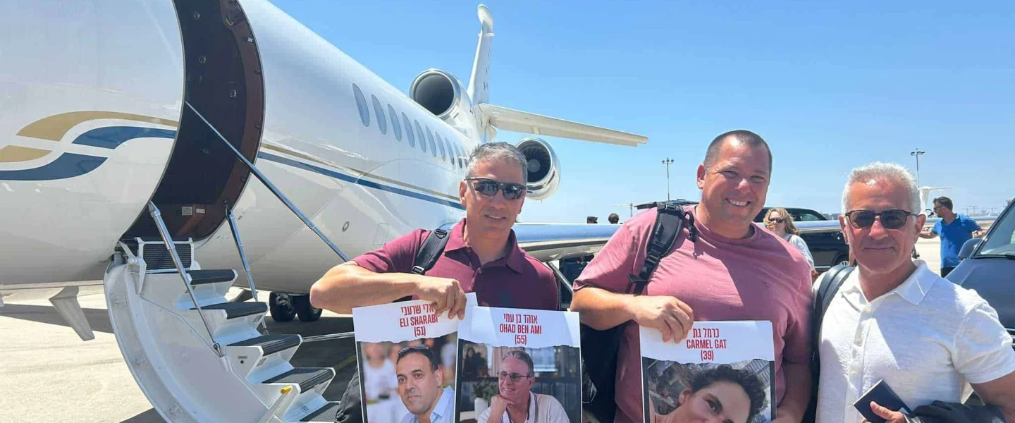 From left: Oct. 7 survivors Sharon Shevo and Avida Bachar and Israel Premier Tech co-owner Sylvan Adams prepare to board a flight to Italy for the Tour de France, at Ben Gurion Airport, June 26, 2024. Photo by Amelie Botbol.