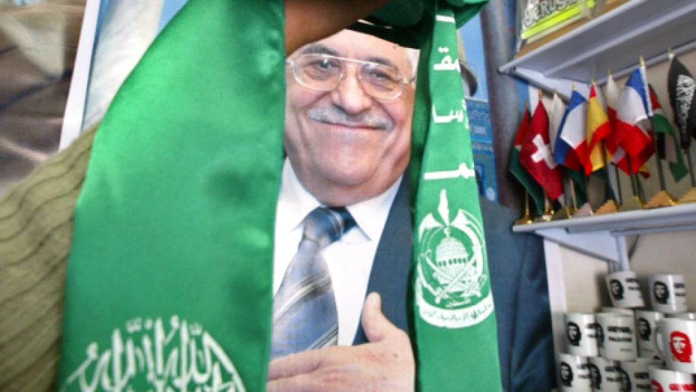 Gaza City, Gaza Strip on Feb. 7, 2006: Palestinian Abu Dayya holds up the Hamas flag in front of a poster of Mahmoud Abbas in his shop in Gaza City. Photo by Ahmad Khateib/Flash90.