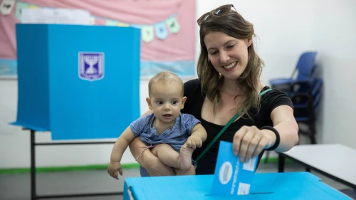 A woman holds her baby as she casts her ballot at a voting station in Jerusalem during the second round of Israeli elections on Sept. 17, 2019. Photo by Yonatan Sindel/Flash90.