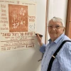Michael Smuss points to a poster commemorating the 50th anniversary of the Warsaw Ghetto Uprising in 1993. Credit: Courtesy.