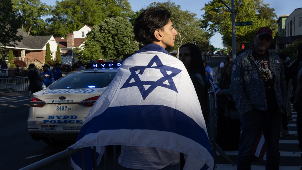 A supporter of Israel stands outside the Young Israel of Jamaica Estates synagogue, which hosted a sale of land in Judea and Samaria, in the Queens borough of New York City, May 12, 2026. Protesters have attempted to disrupt such events, alleging the sales are illegal. Photo by Andrew Lichtenstein/Corbis via Getty Images.