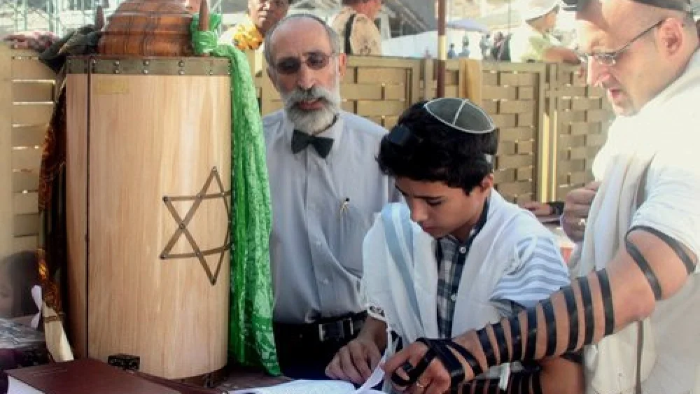 A bar mitzvah boy reads his Torah portion at the Western Wall in Jerusalem. Photo by Peter van der Sluijs via Wikimedia Commons.