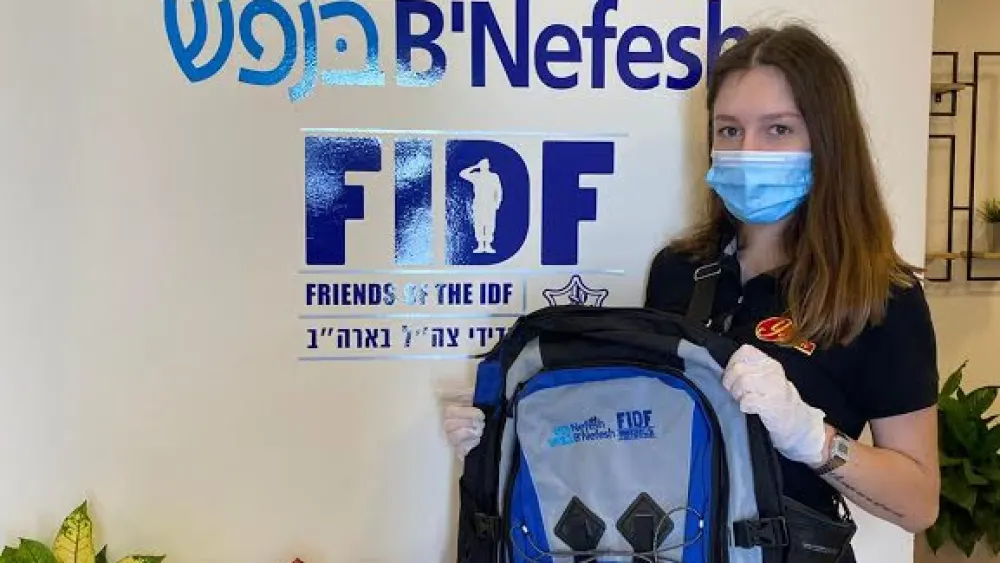 A lone soldier and new recruit in the Israel Defense Forces holds up an official backpack, April 2020. Credit: Courtesy.
