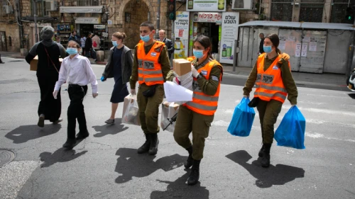 Israeli soldiers in the Home Front Command Unit give out food packages to elderly people in Jerusalem obliged to stay home due to the coronavirus pandemic, April 7, 2020. Photo by Olivier Fitoussi/Flash90.