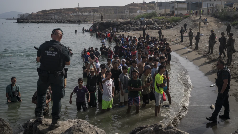 Members of the Guardia Civil USECIC guard migrants on Tarajal beach after they crossed the border between Spain and Morocco in Ceuta, Spain, on July 31, 2026. Photo by Adri Salido/Getty Images.