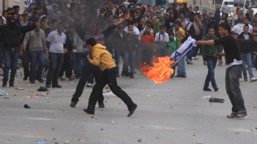 Palestinians burn an Israeli flag during a “Day of Rage” riot at Qalandiya checkpoint near Ramallah in the West Bank, March 16, 2010. Photo by Issam Rimawi/Flash90.