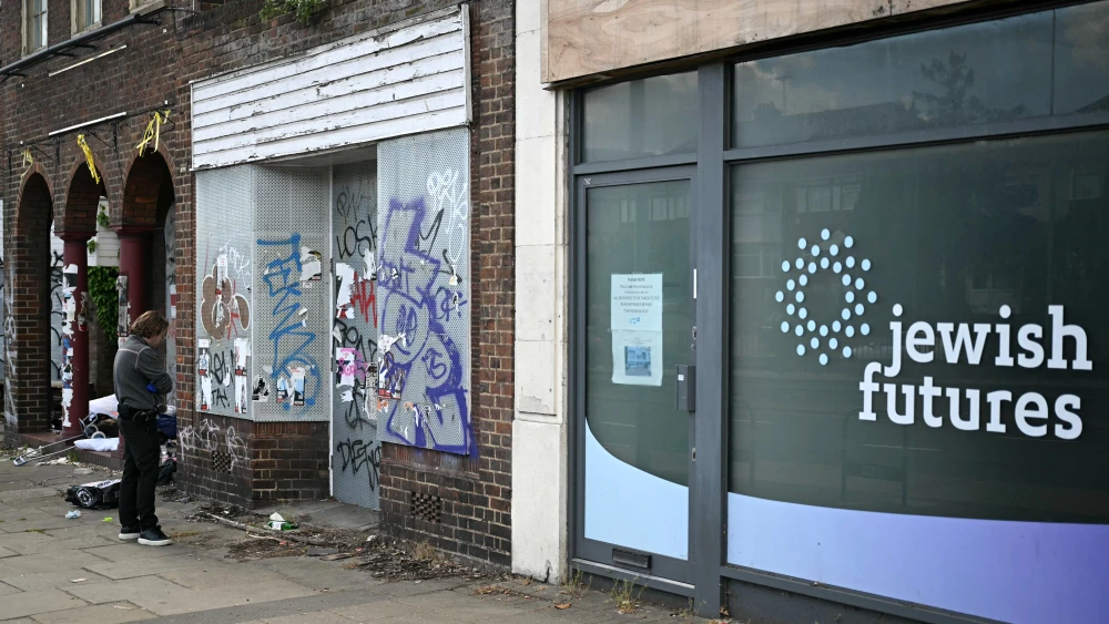 A police officer looks at a glass bottle during an investigation into an arson attack, beside an office formerly used by the business "Jewish futures" in Hendon, north London.