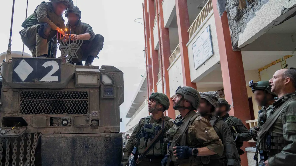 Israeli soldiers in the Gaza Strip light a menorah for the third night of Chanukah, Dec. 9, 2023. Credit: IDF.