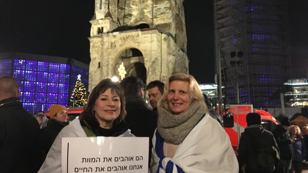 During a Dec. 19 demonstration outside the Kaiser Wilhelm Memorial Church in Berlin, coinciding with the anniversary of the 2016 Christmas market terror attack in that city, the woman pictured at left holds a Hebrew-language sign reading, "They love death, we love life.” At right is Antje Böttinger, a non-Jewish German who wrapped herself in an Israeli flag. Credit: Orit Arfa.