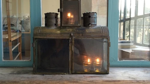 Yael Scalia Hershberg's Hanukkah menorah, in which nine shot glasses filled with olive oil (and each topped with a wick) are placed in a simple box fashioned of brass and tin. The box was purchased from a craftsman in the Jerusalem neighborhood of Mea Shearim. Credit: Yael Scalia Hershberg.