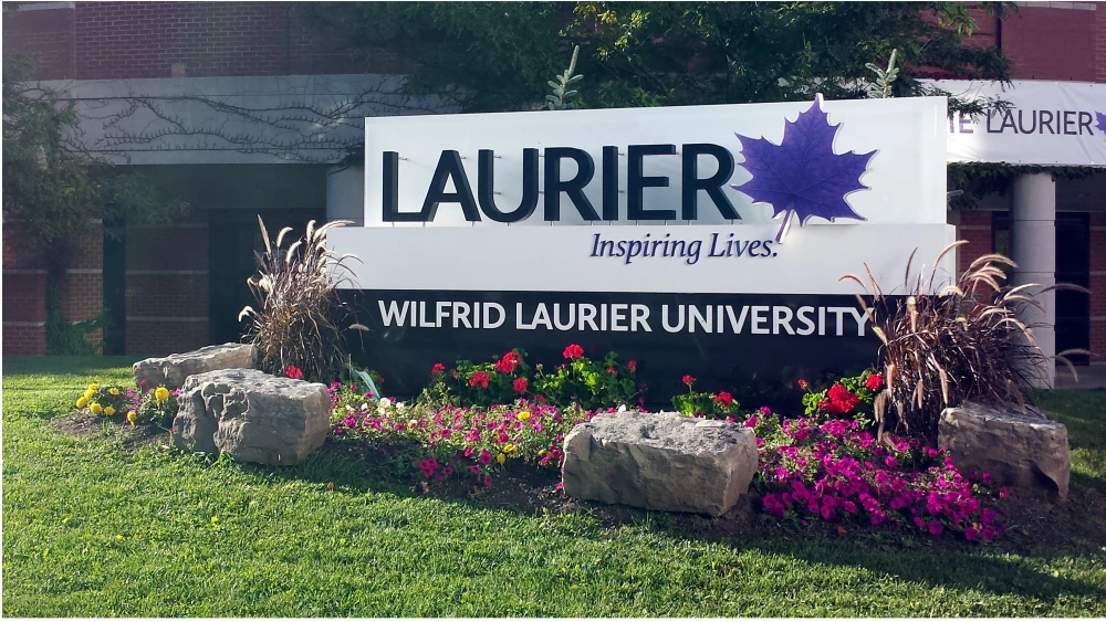 A sign for Wilfrid Laurier University at the intersection of King St. North and Bricker Ave., in Waterloo, Ontario. Credit: GatorEG via Wikimedia Commons.
