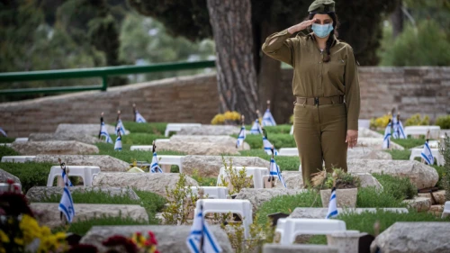 An IDF soldier participates in the annual ceremony, ahead of Memorial Day, of laying Israeli flags on the graves of fallen soldiers at the Mount Herzl military cemetery in Jerusalem, April 11, 2021. Photo by Yonatan Sindel/Flash90.