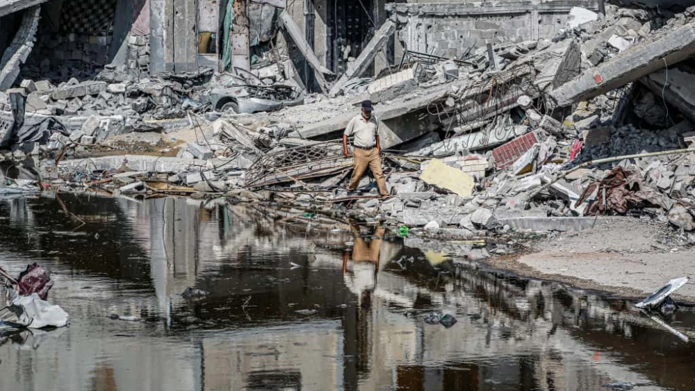 A man walks past destroyed buildings and sewage water erupting from collapsed underground pipes in Khan Yunis, in the southern Gaza Strip, July 8, 2024. Photo by Bashar Taleb/AFP via Getty Images.