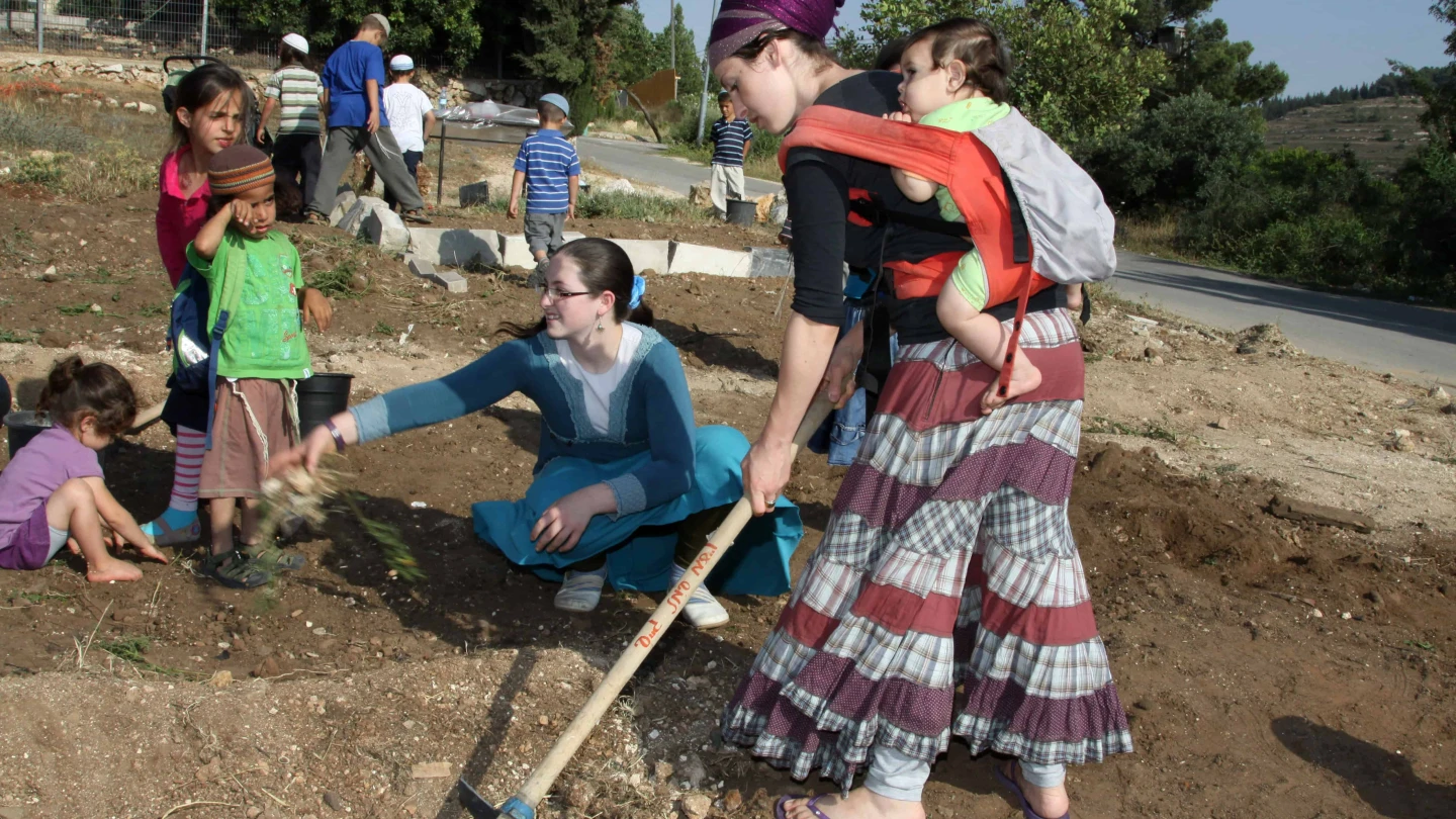 Women and children from Jewish settler families work on a plot to plant flowers and vegetables for a community garden project in the West Bank Jewish settlement of Bat Ayin in Gush Etzion, near Jerusalem, on May 21, 2013. Photo by Gershon Elinson/Flash90. îúðçìéí âéðä òáåãä òáåãåú âéðåï òáåãú âéðåï òåáãéí á âéðä àãîä çì÷ä éùåá âéðä ÷äéìúéú îùåúôú òáåã àãîä îòáãéí ôøçéí éø÷åú áú òéï ééùåá ÷äéìúé ëôøé ãúé äúðçìåú á îòøá âåù òöéåï