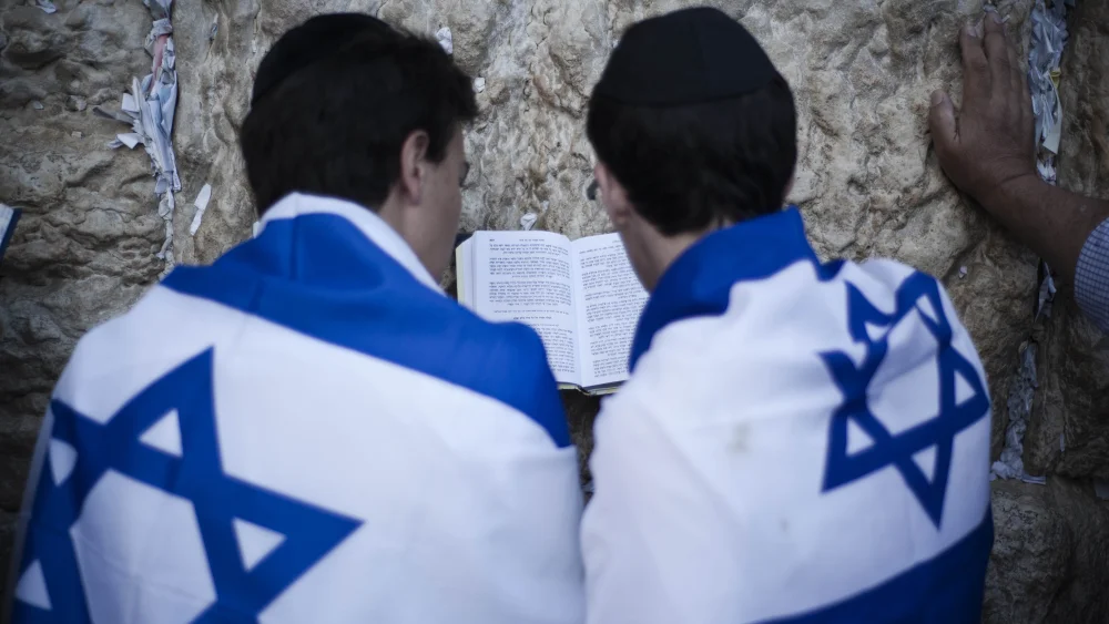 Young Israelis wrapped in the Israeli flag pray at the Western Wall in Jerusalem. Photo by Ruben Salvadori / Flash 90.