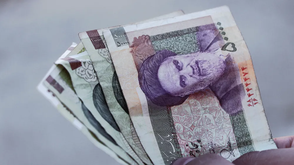 A person holding Iranian rial banknotes. Credit: Amir Ghoorchiani/Pexels.