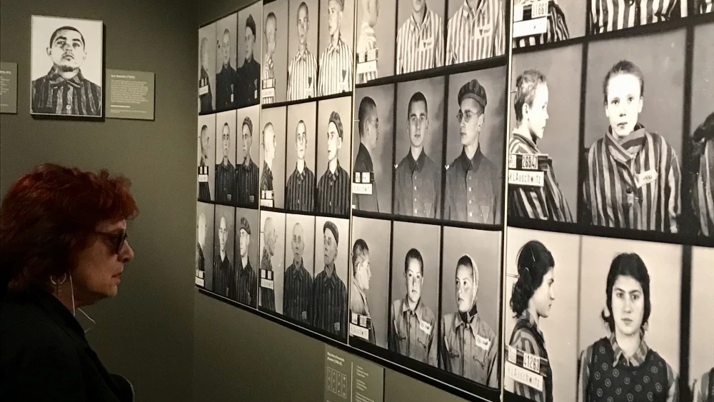 A visitor of the exhibit looking at mug shots of Auschwitz prisoners on display at “Auschwitz: Not long ago. Not far away.” Credit: Shiryn Ghermezian.