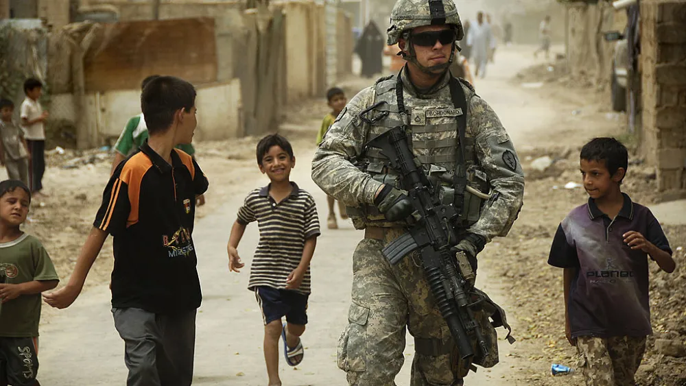 Iraqi children gather around as U.S. Army Pfc. Shane Bordonado patrols the streets of Al Asiriyah, Iraq, on Aug. 4, 2008. Credit: U.S. Army via Wikimedia Commons.