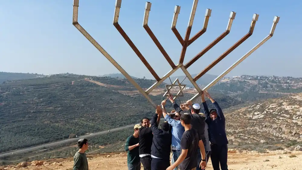 A delegation from Great Neck, N.Y., joins local youth to raise a large Chanukah menorah over the Shiloh Valley in Israel on Dec. 9, 2022. Credit: Courtesy of the Heartland Initiative.