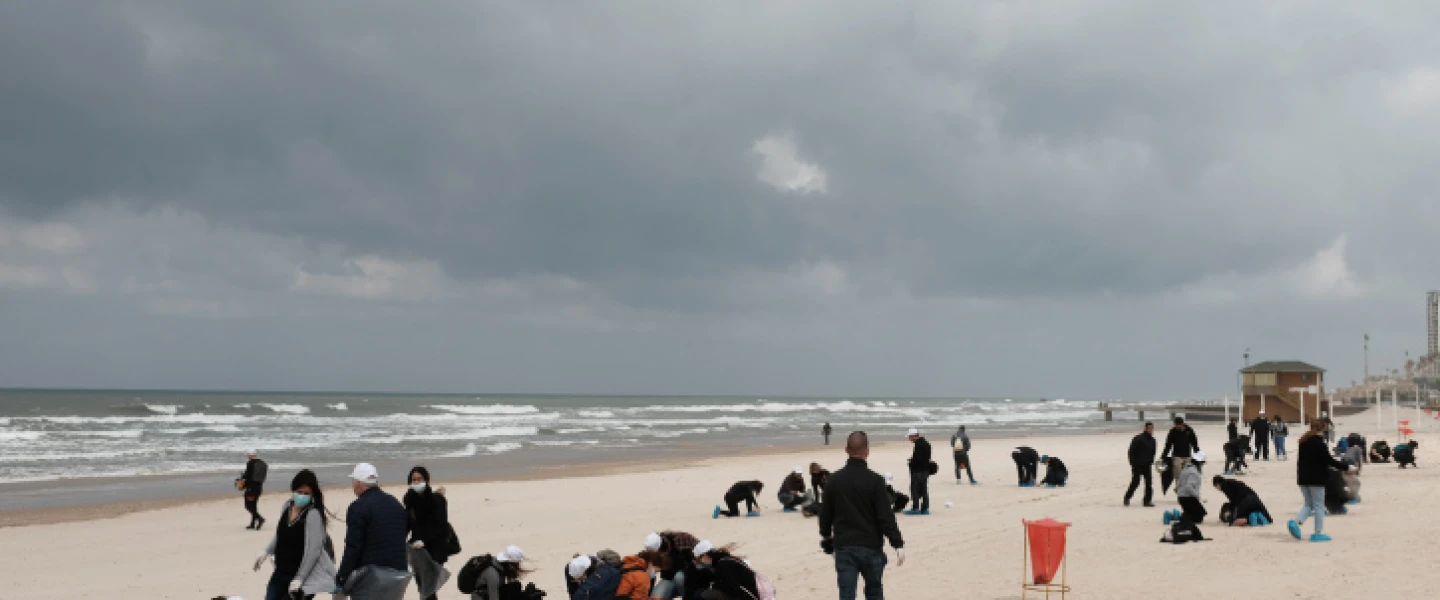 Israelis clean tar off the Bat Yam beach following an offshore oil spill that drenched most of the Israeli coastline, March 2, 2021. Photo by Tomer Neuberg/Flash90.