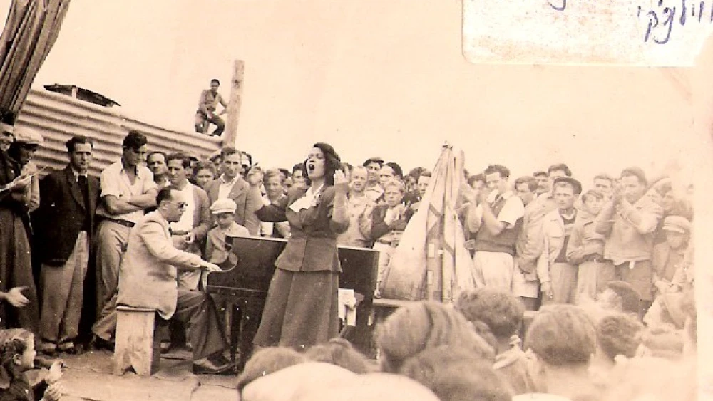 Moshe Vilenski playing piano, and Shoshana Damari singing, entertaining people in Displaced Persons camps in Cyprus, circa 1947-48. Credit: Archive Ein Hashofet via Wikimedia Commons.