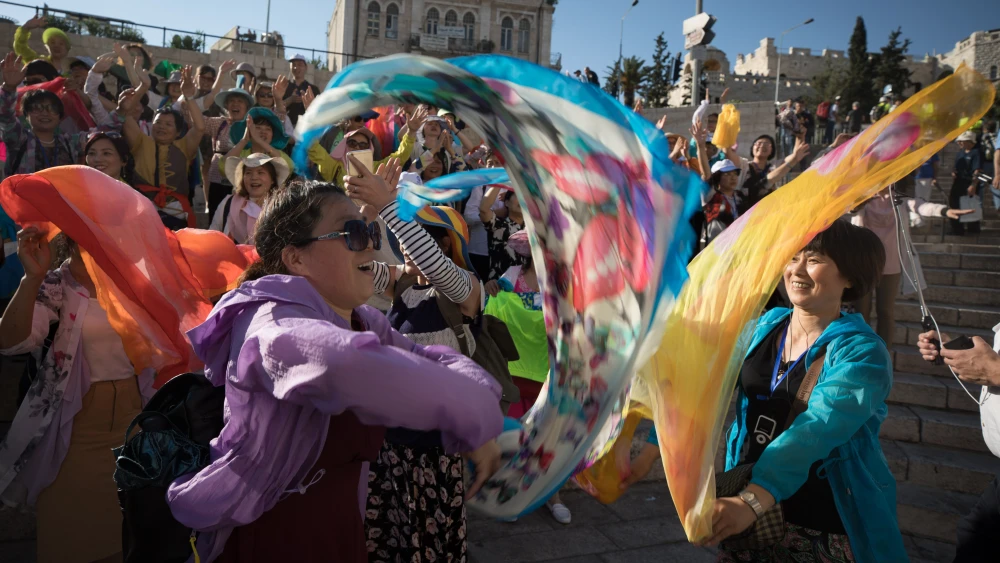 Asian tourists sing and celebrate outside the Damascus Gate in the Old City of Jerusalem on “Jerusalem Day” on May 24, 2017. Credit: Nati Shohat/Flash90.