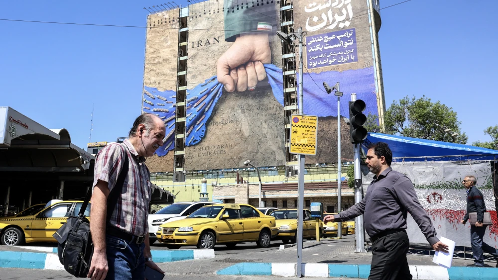 Iranians walk past a large billboard referring to the Strait of Hormuz in Tehran's Vanak Square on April 15, 2026. Photo by AFP via Getty Images.