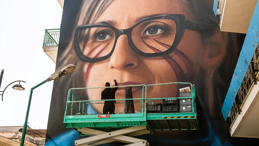 Ciro Ferullo (aka Jorit) works on a mural dedicated to U.N. Special Rapporteur Francesca Albanese in the Barra neighborhood of Naples, Italy, on April 14, 2026. Created to inspire young people, the portrait features lyrics from “Uss” by Luca Persico (O’Zulù) and includes the Neapolitan phrase, “Tutt’ egual song’ ’e criature” (“Children are all the same”), taken from a song by Enzo Avitabile. Photo by Ivan Romano/Getty Images.
