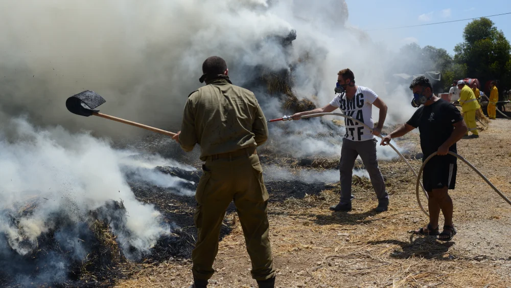 Firefighters and security teams put out a fire that broke up in a cowshed, caused by a kite loaded with an incendiary device launched from Gaza, in Nahal-Oz on July 21, 2018. Photo by Gili Yaari/Flash 90.