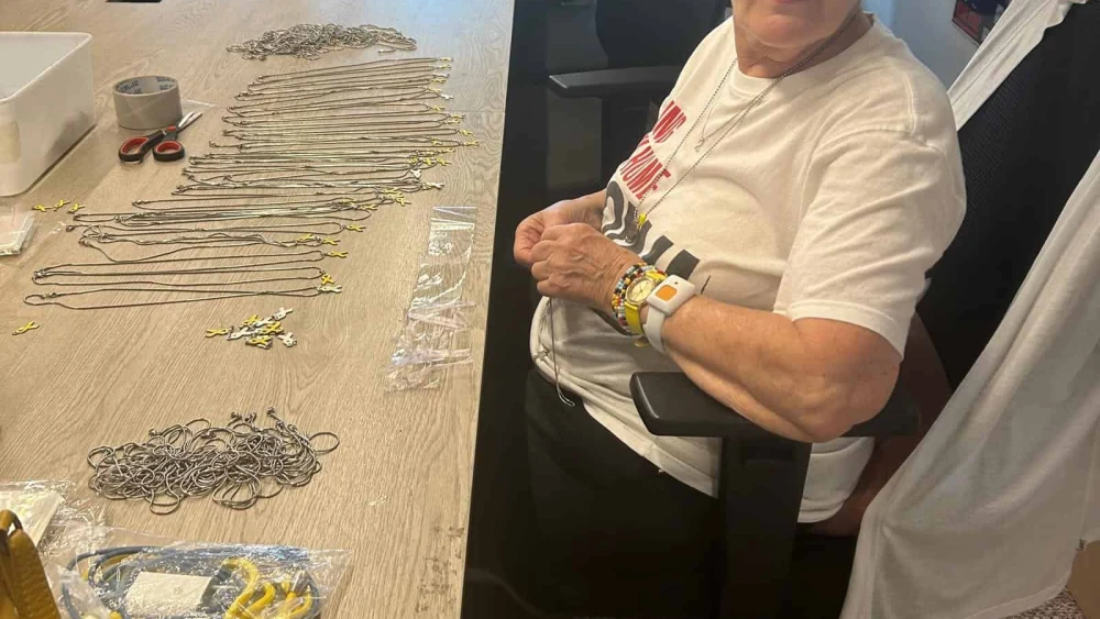 A volunteer makes necklaces with yellow ribbon pendants at the Hostages and Missing Families Forum headquarters in Tel Aviv, to raise awareness and in solidarity with the captives, July 21, 2024. Photo by Amelie Botbol.