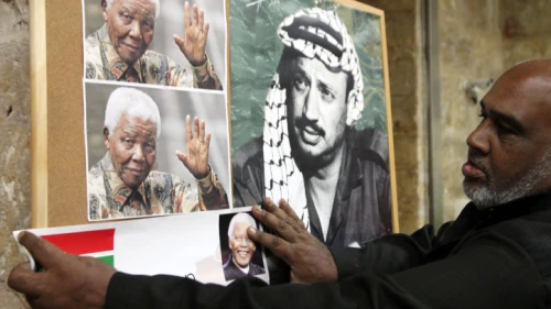 An Arab man hangs a picture of former South African leader Nelson Mandela next to a poster of former PLO chief Yasser Arafat, at a memorial service for Mandela in Jerusalem's Old City, Dec. 8, 2013. Photo by Sliman Khader/Flash90.