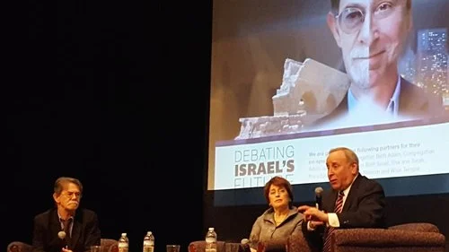 J.J. Goldberg (left) and Jonathan Tobin (right) during one of their debates, in Cincinnati, with a split-screen graphic of their faces on the projector in the background. Credit: Courtesy of J.J. Goldberg/Jonathan Tobin debate tour.
